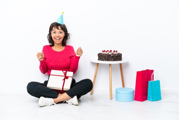 Jovem comemorando seu aniversário sentado no chão isolado no fundo branco comemorando uma vitória na posição de vencedor