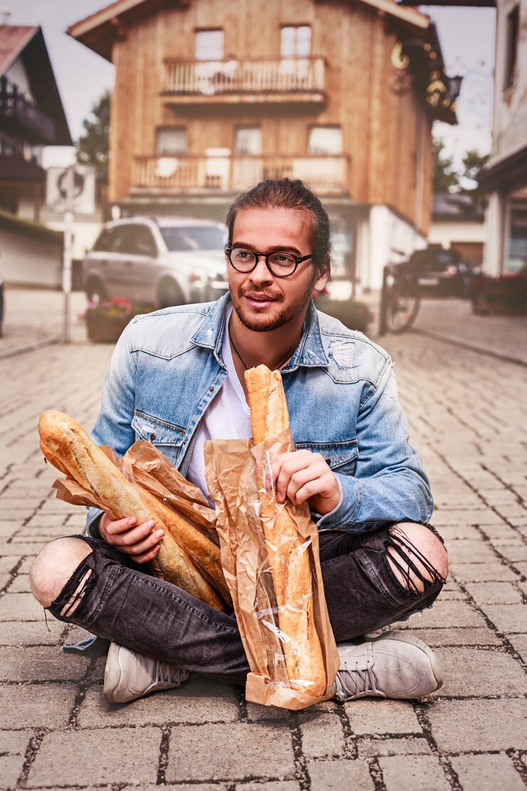 Foto jovem comendo pão sentado na rua