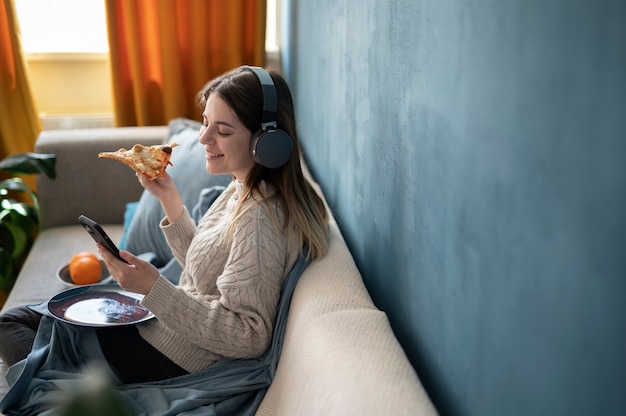 Jovem comendo pizza e ouvindo música