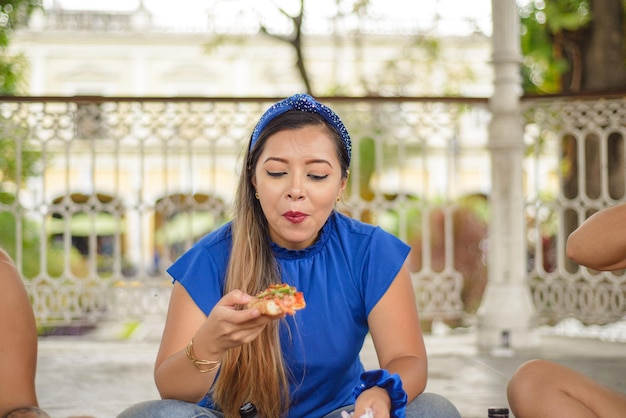 Jovem comendo pizza Jovem sentada comendo pizza mexicana com amigos