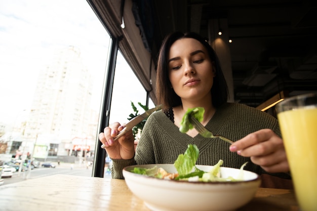 Foto jovem comendo salada no restaurante. conceito de comida saudável.