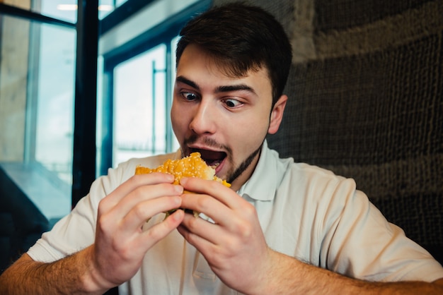 Jovem comendo um hambúrguer em um restaurante