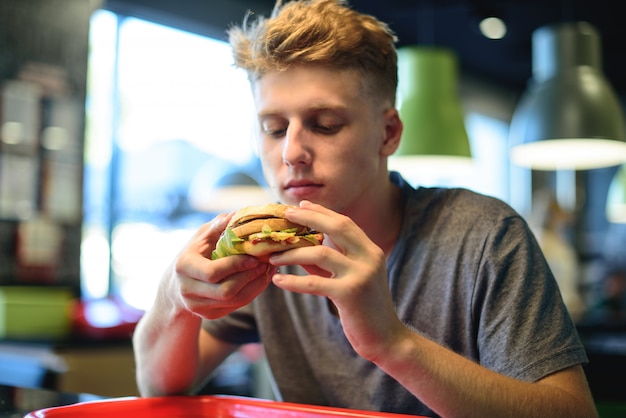 Foto jovem comendo um hambúrguer