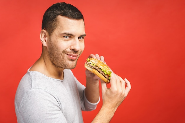 Foto jovem comendo um pedaço de hambúrguer.