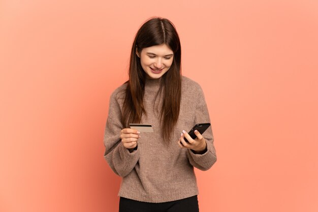 Jovem comprando com o celular com um cartão de crédito