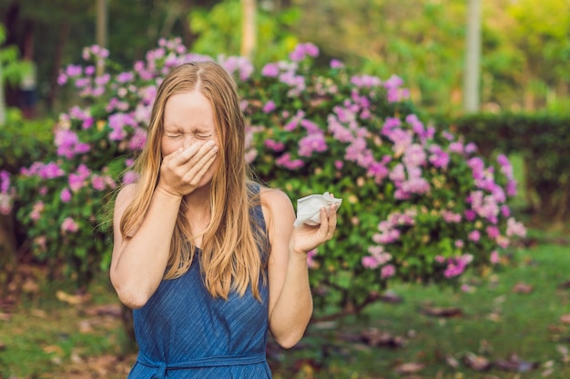 Foto jovem, conceito de alergia ao pólen, vai espirrar árvores floridas no fundo