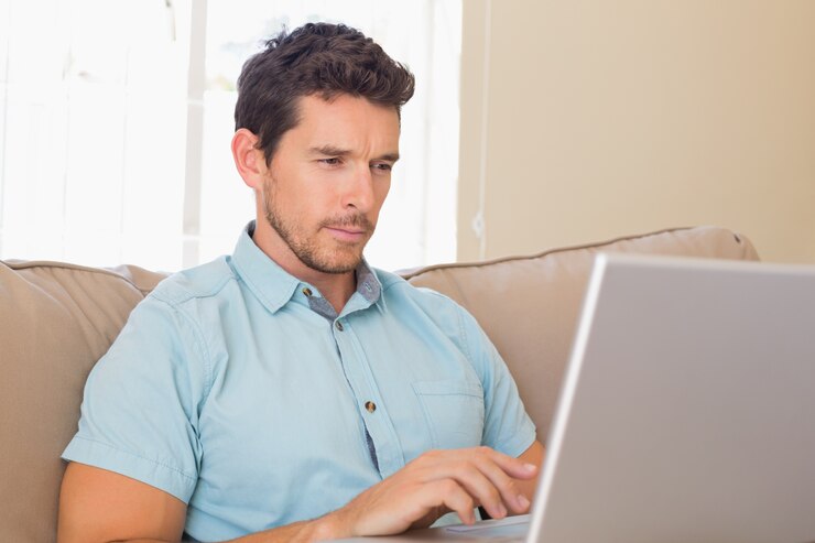 Foto jovem concentrado usando laptop no sofá