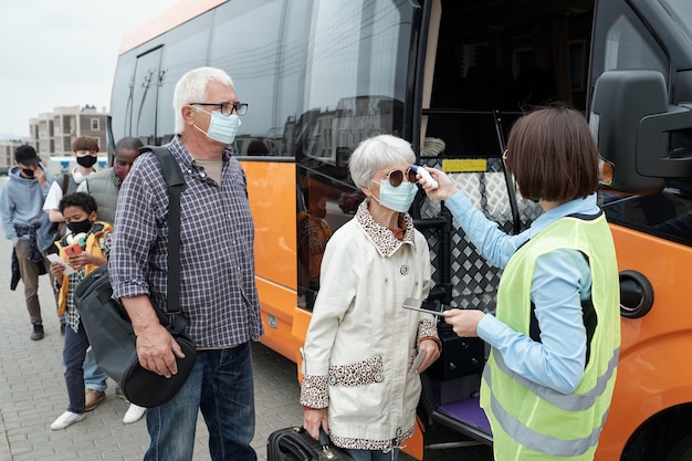 Jovem condutor de ônibus verificando a temperatura corporal dos passageiros