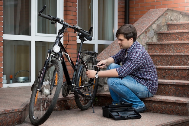 Jovem consertando roda traseira de bicicleta