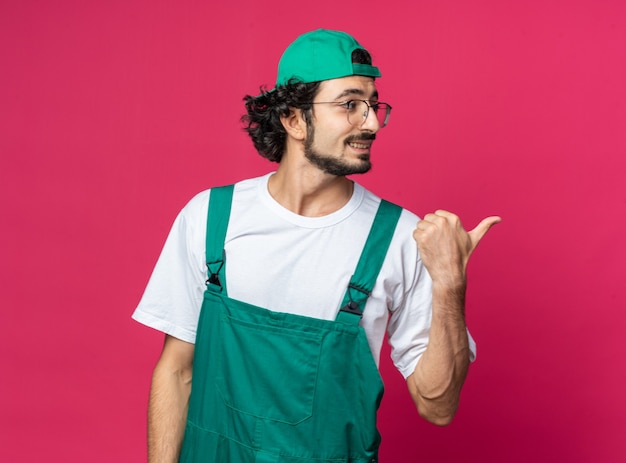 Jovem construtor olhando de lado sorrindo, usando uniforme com pontas nas laterais