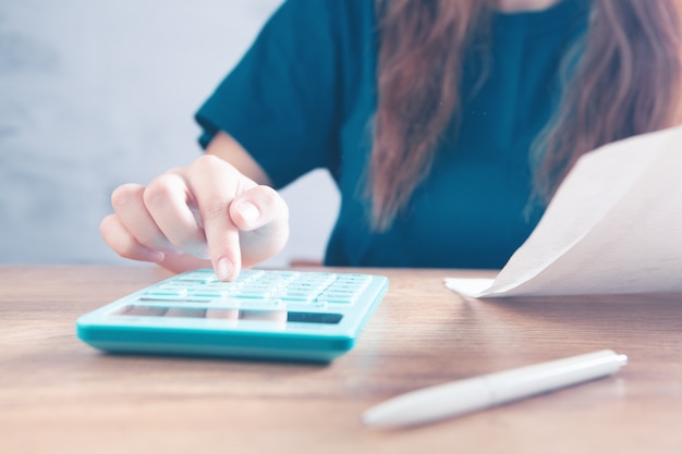 jovem conta com calculadora e faz anotações em papéis