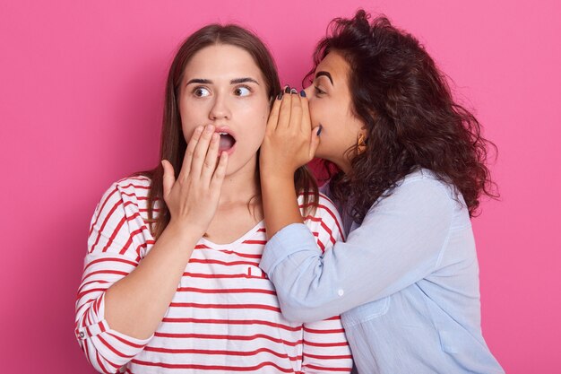 Foto jovem contando a sua namorada um segredo, duas mulheres fofocando. mulher emocional animada em pé