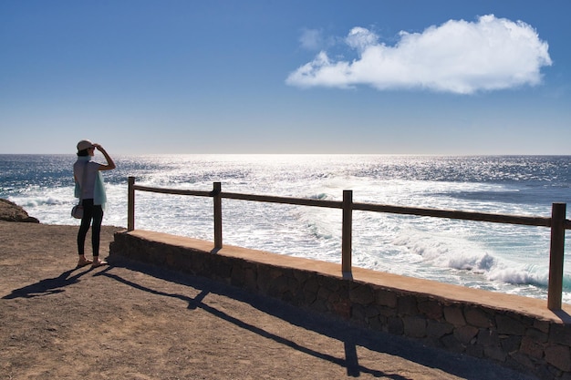 Jovem contemplando as ondas do mar no farol de Jandia em Fuerteventura