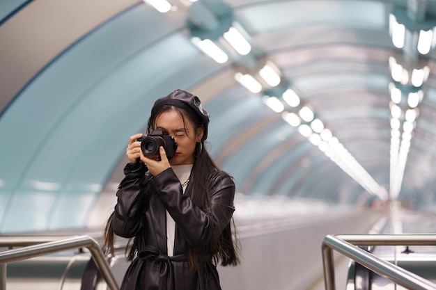 Jovem coreana estilosa faz fotos na câmera no transporte urbano andando de escada rolante enquanto viaja