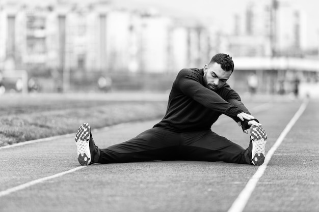 Jovem corredor de fitness esticando as pernas antes de correr