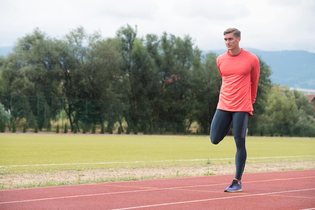 Jovem corredor de fitness esticando as pernas antes de correr