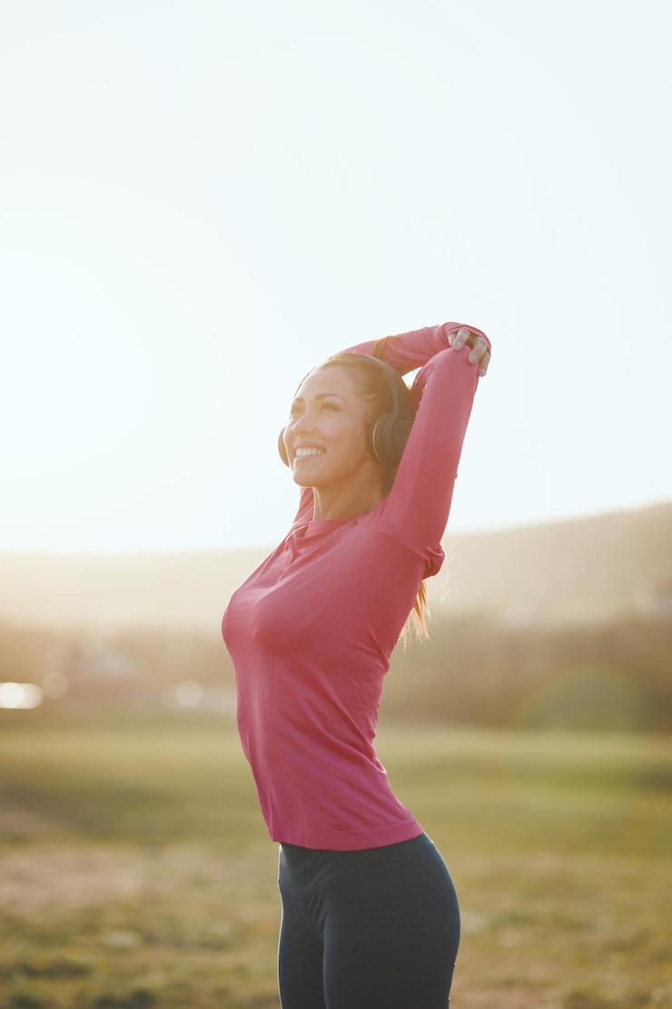 Foto jovem corredor feminino feliz bonito ouvindo música e alongamento antes de correr ao pôr do sol nas montanhas.