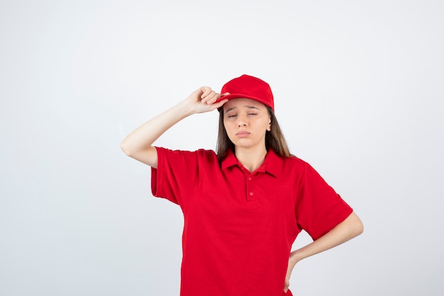 Foto jovem correio feminino em uniforme vermelho, cansando-se depois de muito trabalho.