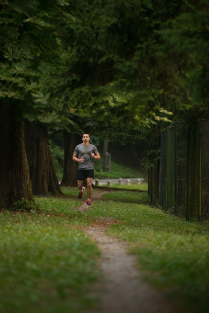 Jovem correndo na área de floresta arborizada - treinamento e exercício para Trail Run Maratona Endurance - conceito de estilo de vida saudável de fitness