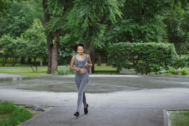 Jovem correndo por um caminho em um parque verde