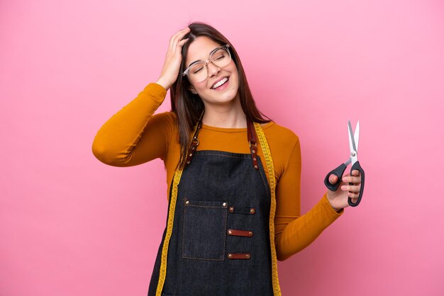 Jovem costureira brasileira isolada em fundo rosa sorrindo muito