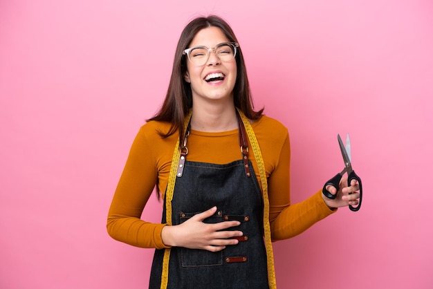 Jovem costureira brasileira isolada em fundo rosa sorrindo muito