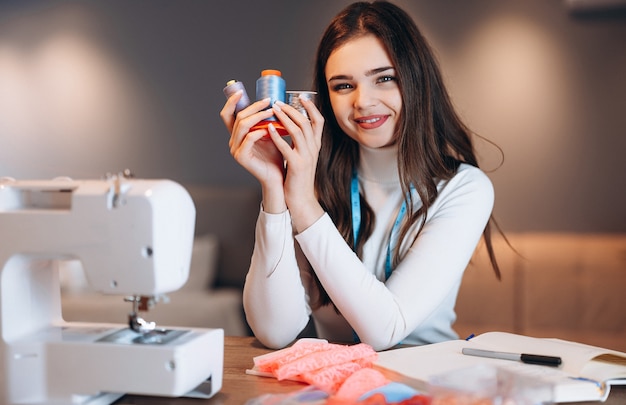 Jovem costureira costura roupas em máquina de costura