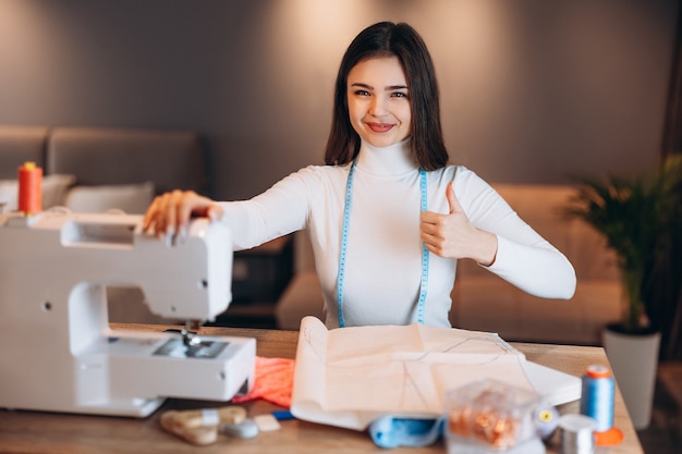 Jovem costureira costura roupas em máquina de costura