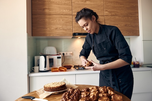 Jovem cozinheira profissional preparando um bolo saboroso em sua cozinha moderna e leve