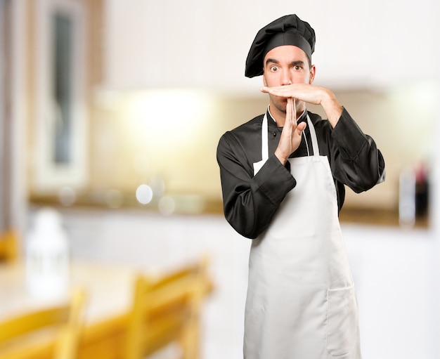 Jovem cozinheiro fazendo um gesto de intervalo