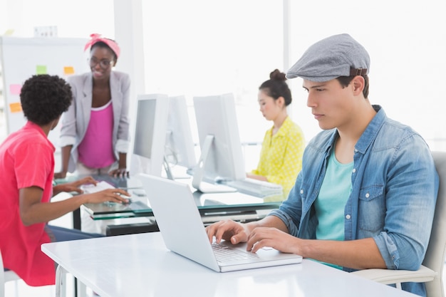 Jovem, criativo, homem, usando, laptop, escrivaninha