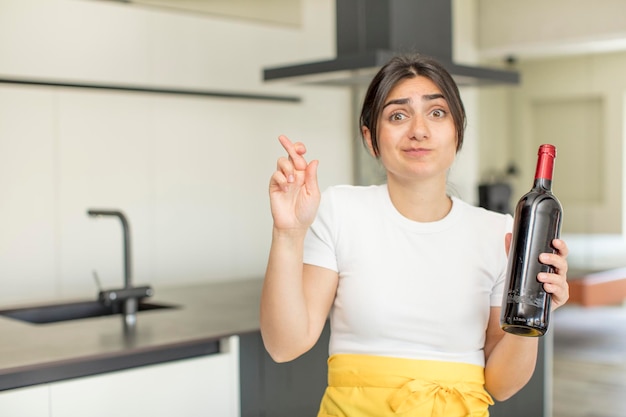 jovem cruzando os dedos e esperando boa sorte no conceito de garrafa de vinho