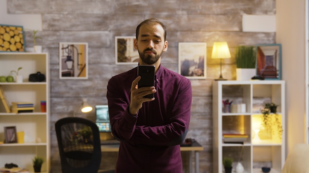 Jovem dando um comando de voz para seu aplicativo de luz inteligente e as luzes estão acesas na casa