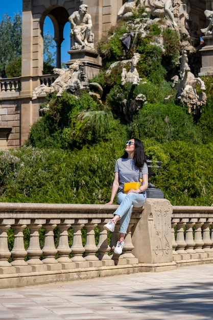 Jovem de 30 anos em camiseta jeans e bolsa amarela andando em um parque Ciutadella em Barcelona Garota viaja na Espanha