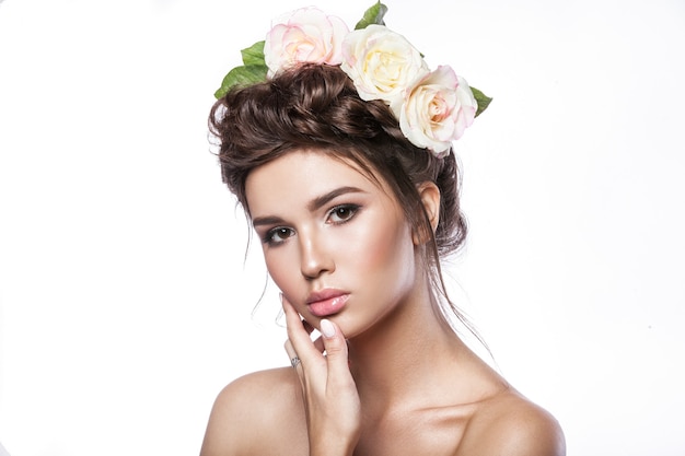 Jovem de beleza, pele limpa, bela maquiagem, tranças de penteado e flores rosas no cabelo.