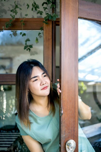 Jovem de cabelo comprido olha pela janela linda mulher asiática garota feliz