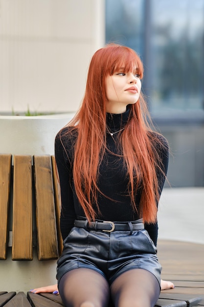 Jovem de cabelo vermelho senta-se pacientemente no banco