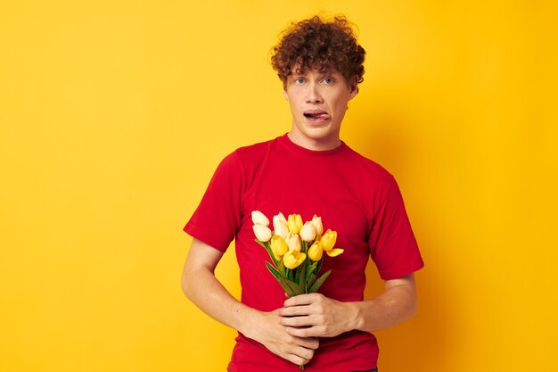 Jovem de cabelos encaracolados em uma camiseta vermelha um buquê de flores presente de feriado estilo de vida inalterado