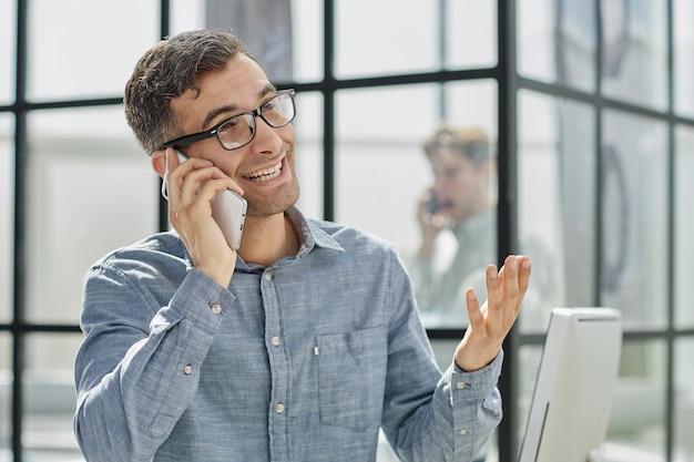 Jovem de camisa azul a falar ao telefone.