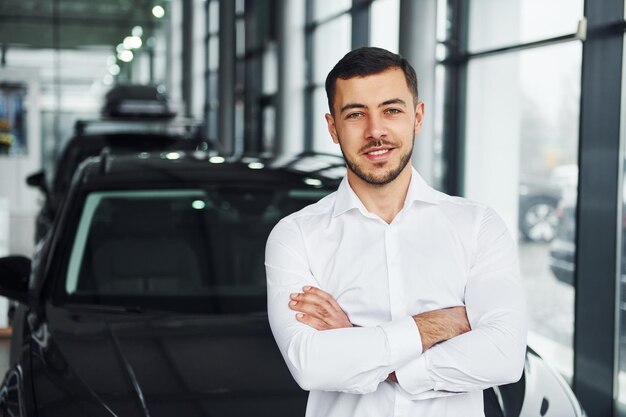 Jovem de camisa branca está dentro de casa com um novo automóvel moderno