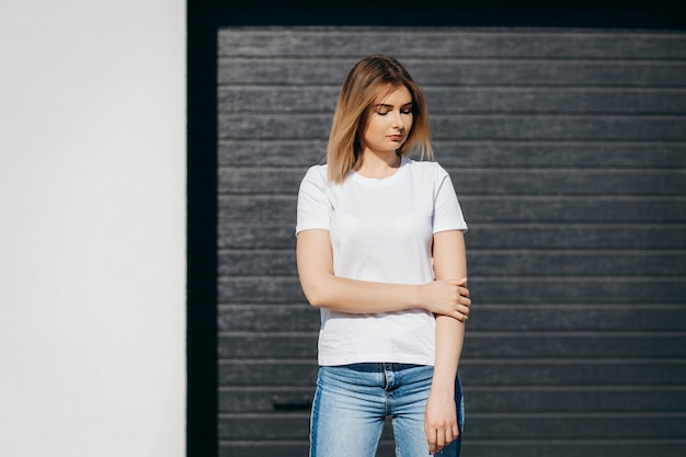 Jovem de camisa e calça jeans posando ao ar livre