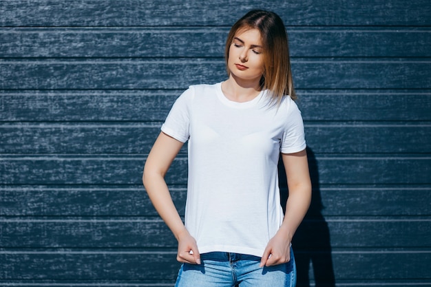 Jovem de camisa e calça jeans posando ao ar livre