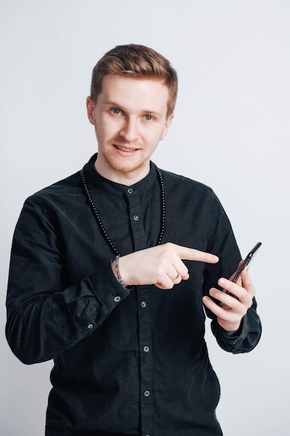 Jovem de camisa preta com um smartphone nas mãos em um fundo branco