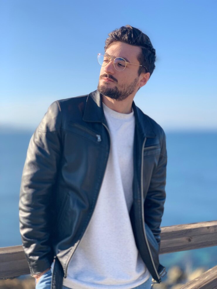 Foto jovem de casaco de couro de pé contra o mar