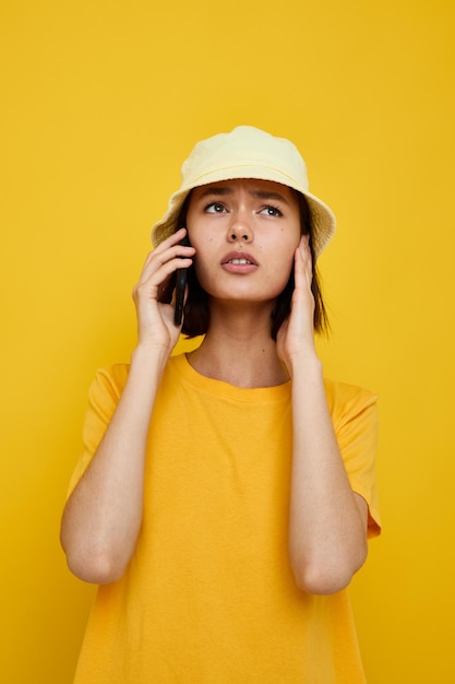 Jovem de chapéu amarelo estilo jovem casual falando ao telefone fundo isolado