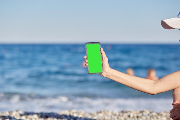 Jovem de chapéu com um telefone na praia perto do mar está fazendo uma selfie Descansando viajando e relaxando o conceito Espaço para cópia Foto de alta qualidade