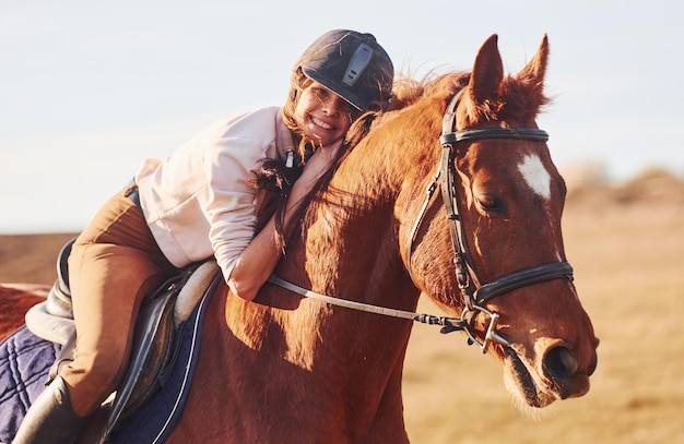 Jovem de chapéu protetor com seu cavalo no campo agrícola no dia ensolarado