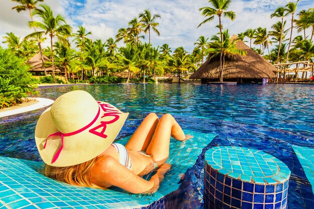 Jovem de chapéu relaxando na piscina