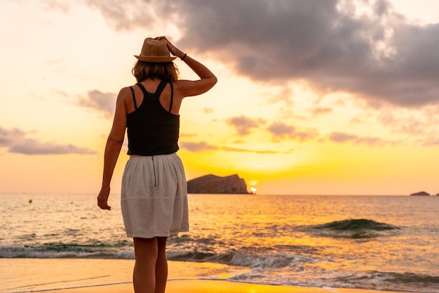 Jovem de férias ao pôr do sol na praia de Cala Comte, na ilha de Ibiza Balearic