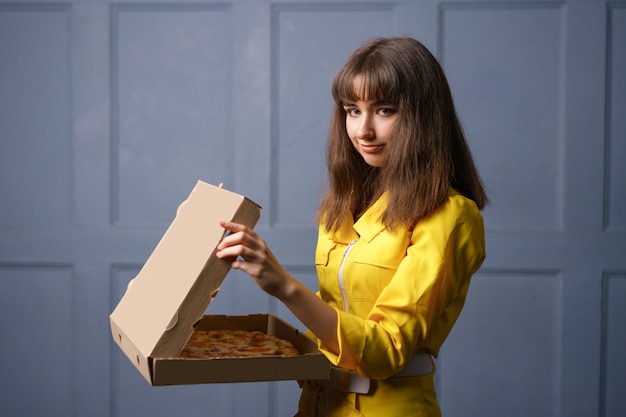 Jovem de macacão amarelo, entregando pizza. o conceito de empresa de pequeno porte